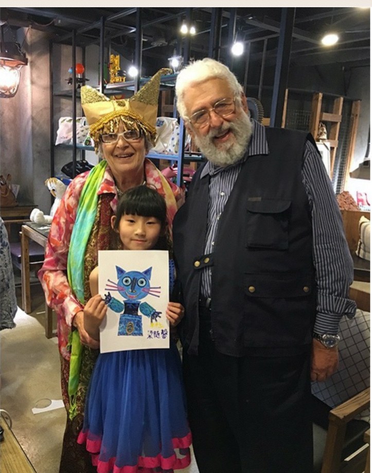 Cristina e Francesco in Cina con una bambina che mostra il disegno di un gatto blu